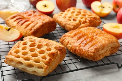 Photo of Delicious puff pastries with fruit filling and apples on grey table, closeup