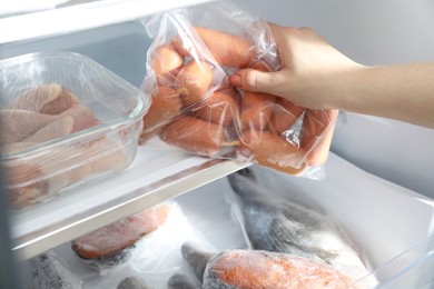 Photo of Woman taking bag of frozen sausages out of fridge, closeup