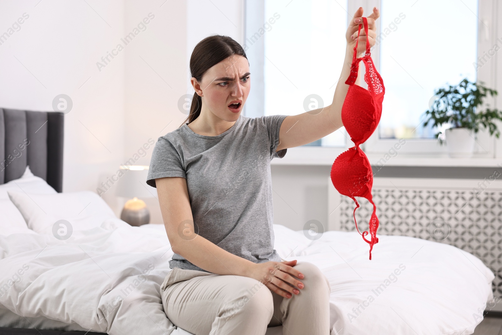 Photo of Surprised wife finding mistress bra in bedroom