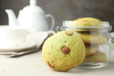 Photo of Delicious mint chocolate chip cookies in jar on light table, closeup. Space for text