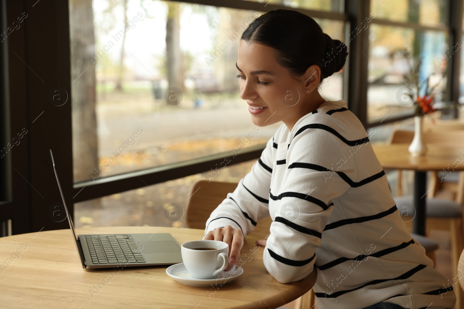 Photo of Woman working on laptop at table in cafe