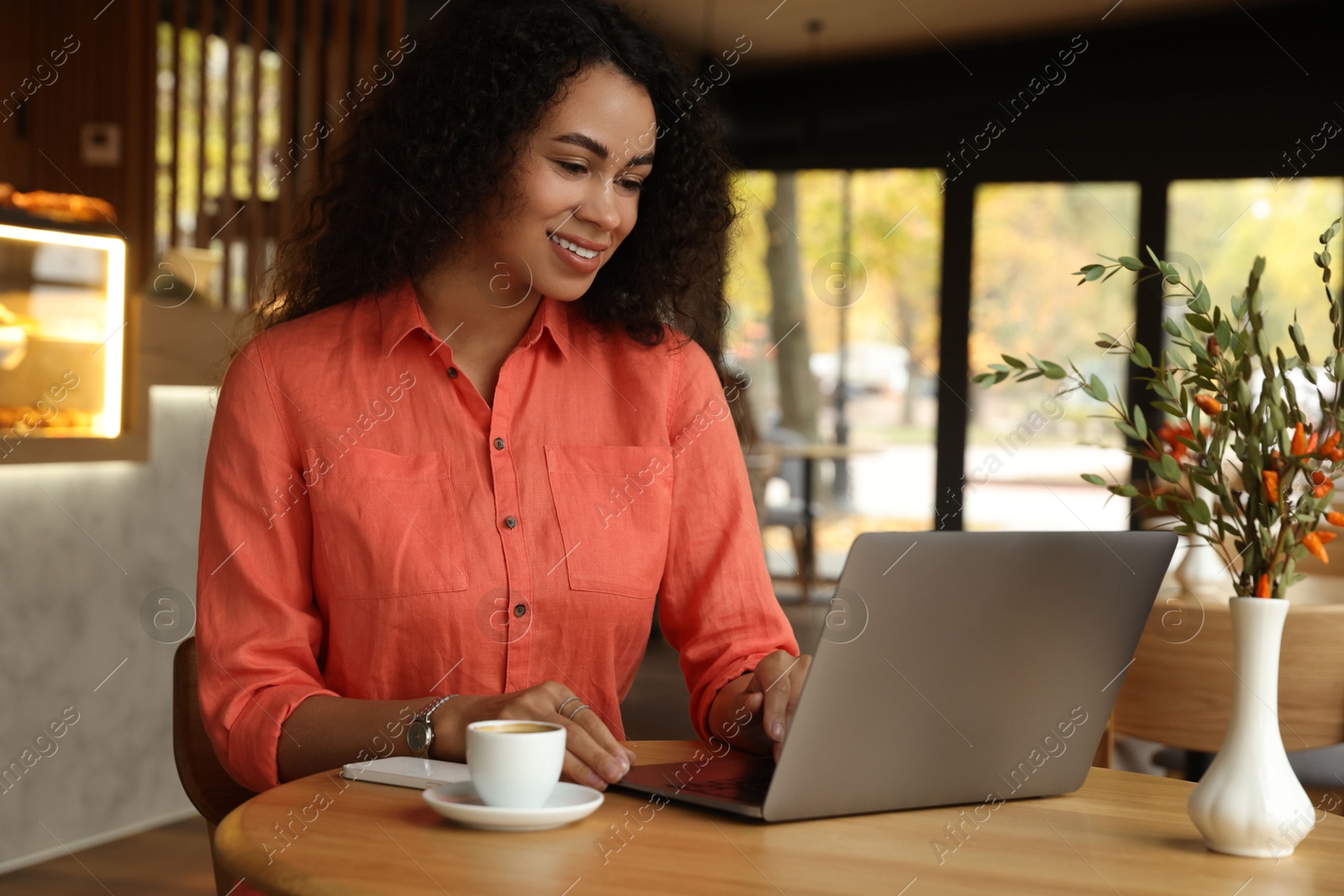 Photo of Woman working on laptop at table in cafe