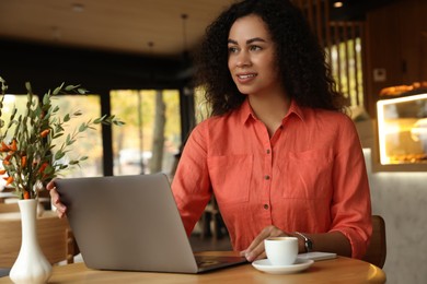 Photo of Woman working on laptop at table in cafe