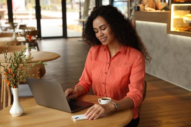 Photo of Woman working on laptop at table in cafe