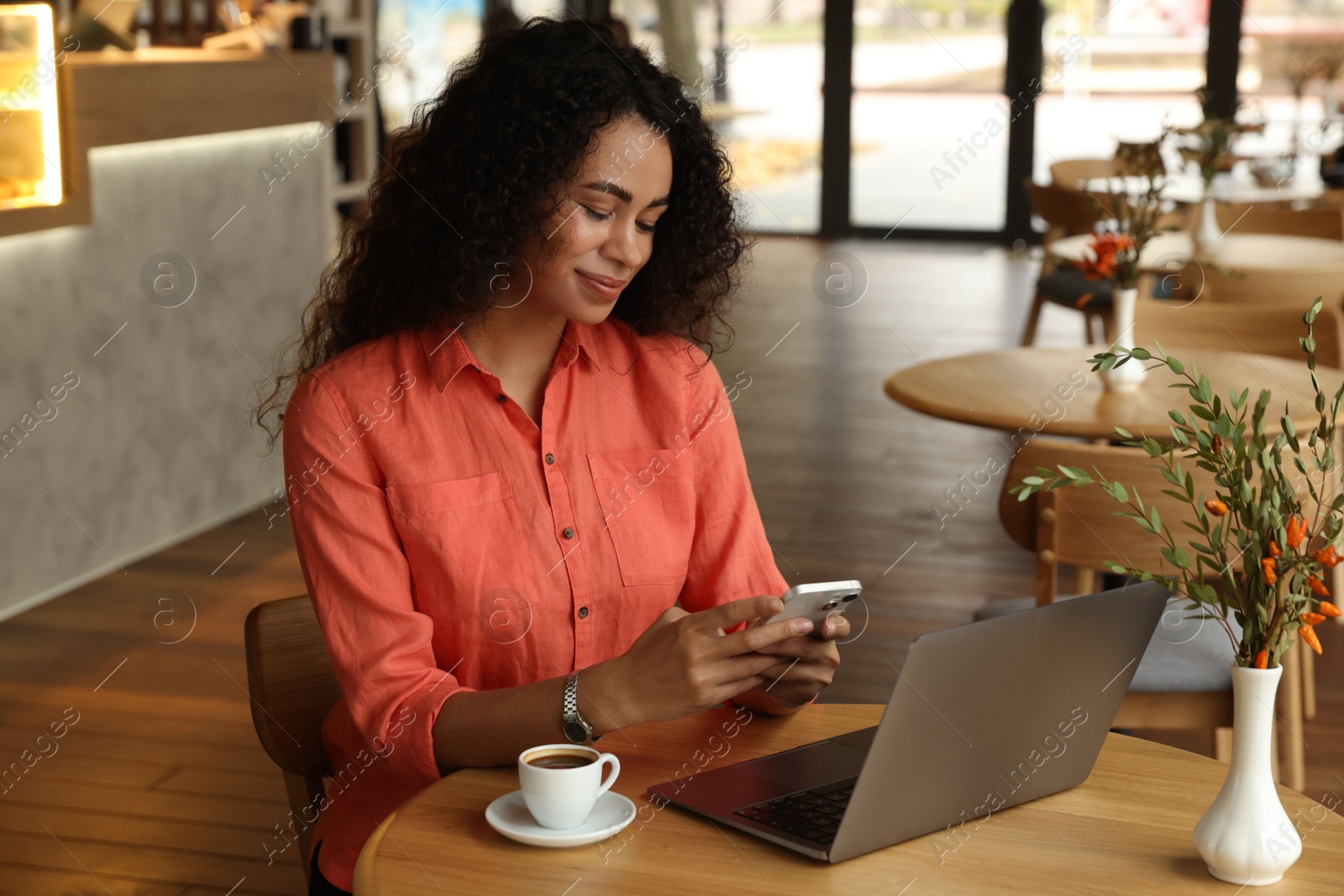 Photo of Woman using smartphone while working in cafe