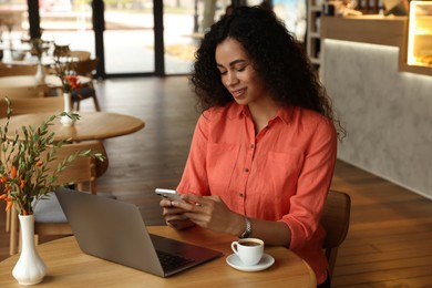 Photo of Woman using smartphone while working in cafe