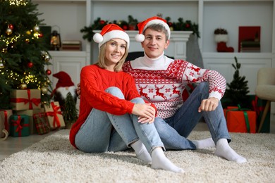 Lovely couple in Santa hats and Christmas sweaters at home