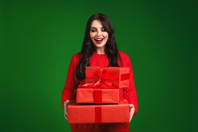 Beautiful woman with Christmas gifts on green background