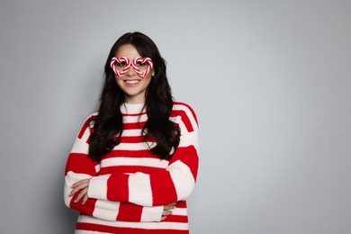 Photo of Happy woman with party glasses on light grey background, space for text. Christmas celebration