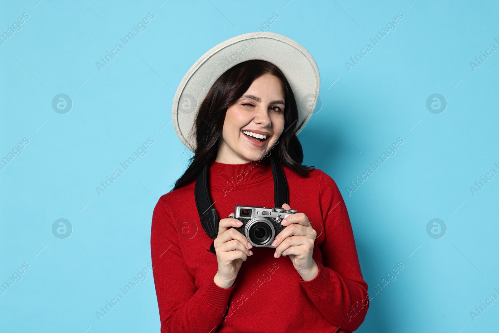 Photo of Young tourist in hat with camera on light blue background