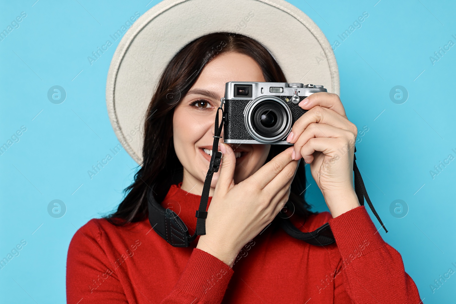 Photo of Young tourist in hat with camera on light blue background