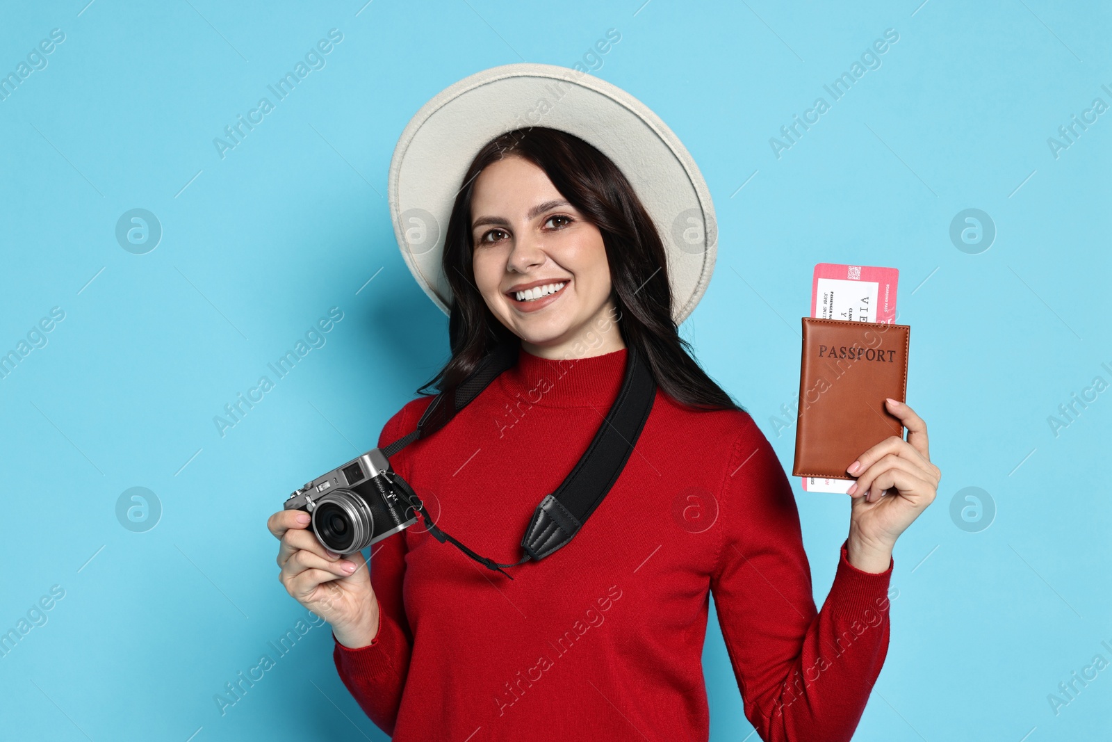 Photo of Young tourist in hat with camera on light blue background