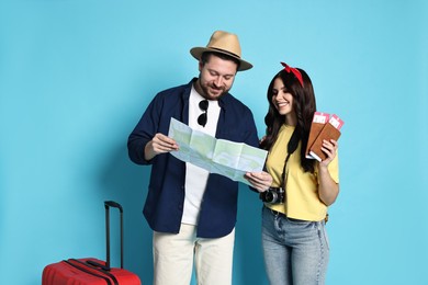 Photo of Tourism. Happy couple with map and suitcase on light blue background