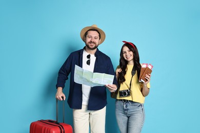 Photo of Tourism. Happy couple with map and suitcase on light blue background