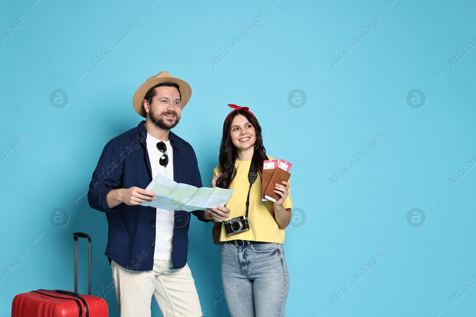 Photo of Tourism. Happy couple with map and suitcase on light blue background