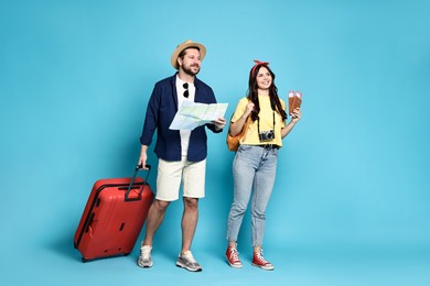 Tourism. Happy couple with map and suitcase on light blue background