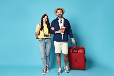 Photo of Tourism. Happy couple with suitcase on light blue background