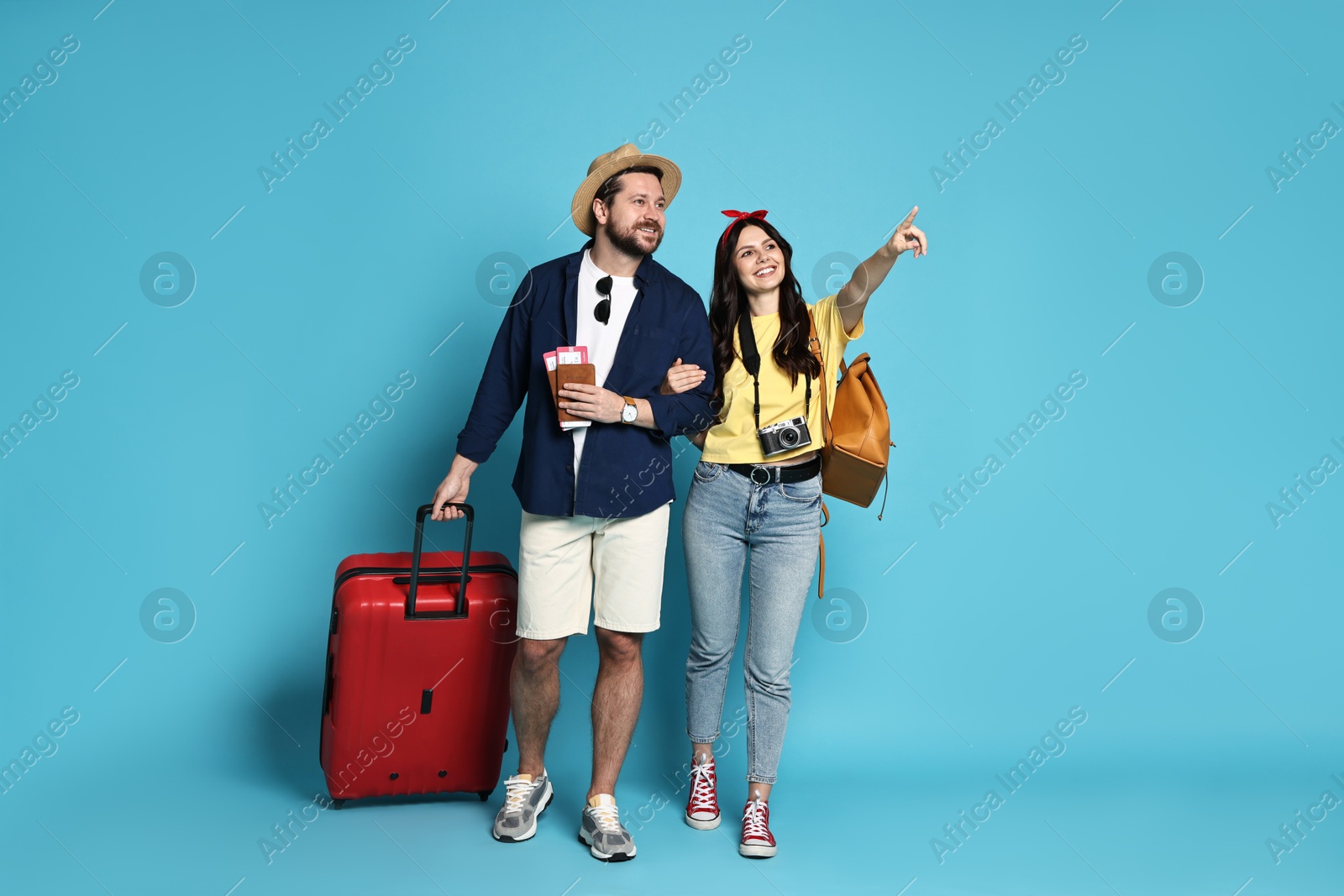 Photo of Tourism. Happy couple with suitcase on light blue background