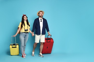 Photo of Tourism. Happy couple with suitcases on light blue background