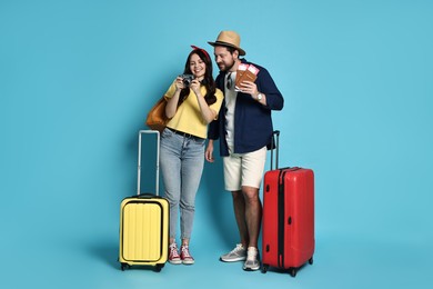 Photo of Tourism. Happy couple with suitcases on light blue background