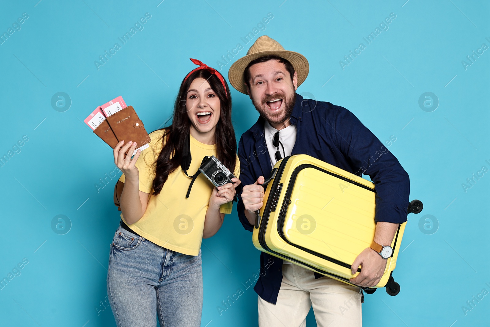 Photo of Tourism. Emotional couple with suitcase on light blue background