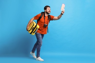 Photo of Traveller with passport, ticket and suitcase on light blue background