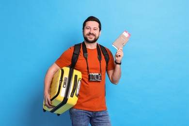 Photo of Traveller with passport, ticket and suitcase on light blue background