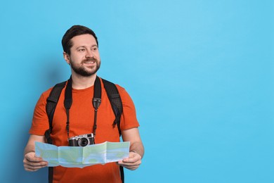 Photo of Traveller with vintage camera and map on light blue background, space for text