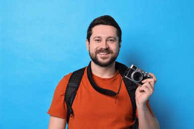 Traveller with vintage camera on light blue background