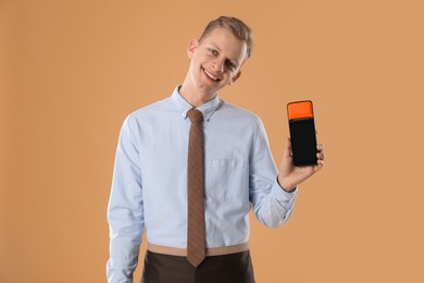 Happy young man with payment terminal on beige background