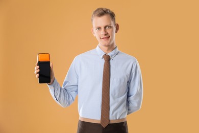 Photo of Happy young man with payment terminal on beige background