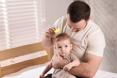 Man brushing hair of his little baby on bed indoors, space for text