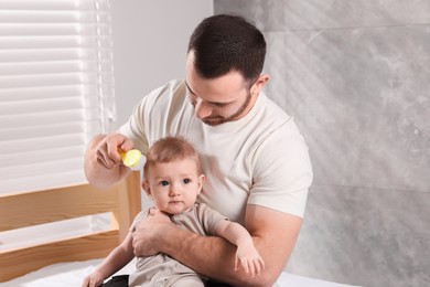 Man brushing hair of his little baby on bed indoors