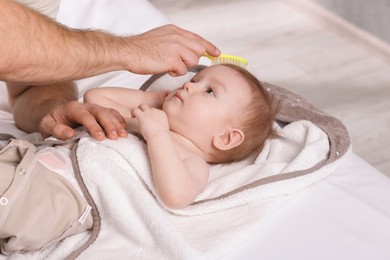 Photo of Man brushing hair of his little baby indoors, closeup