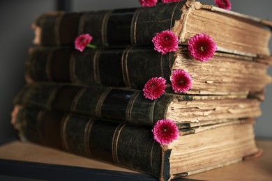 Photo of Stack of books and beautiful flowers on wooden shelf, closeup