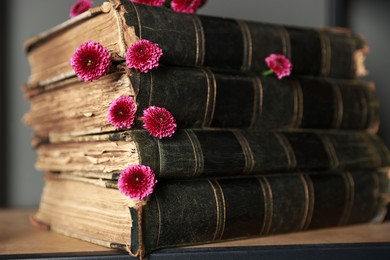 Stack of books and beautiful flowers on wooden shelf, closeup