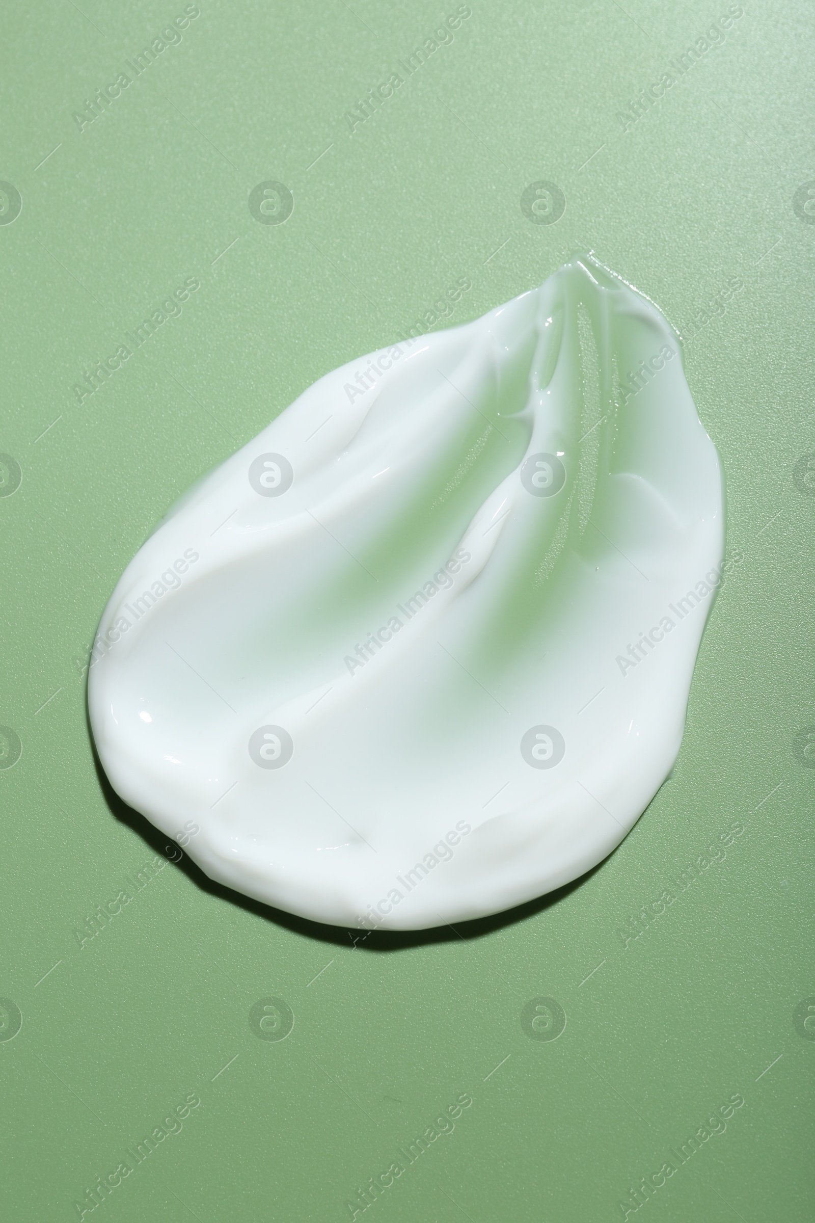 Photo of Cream on green background, top view. Sample of skincare product