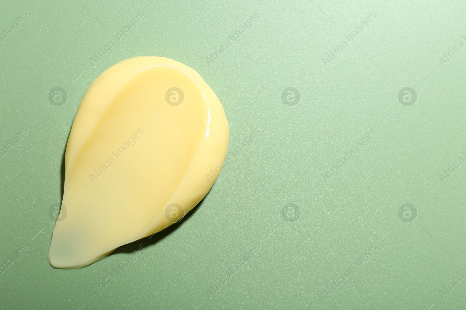 Photo of Cream on green background, top view and space for text. Sample of skincare product