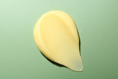 Photo of Cream on green background, top view. Sample of skincare product