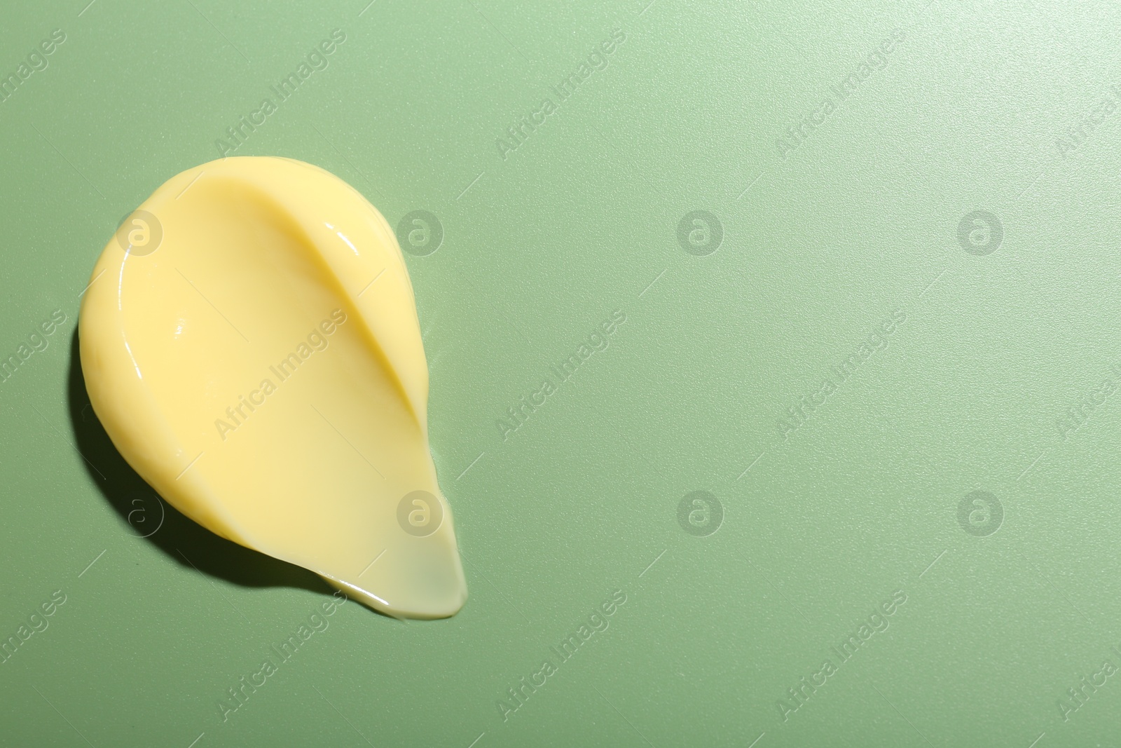 Photo of Cream on green background, top view and space for text. Sample of skincare product