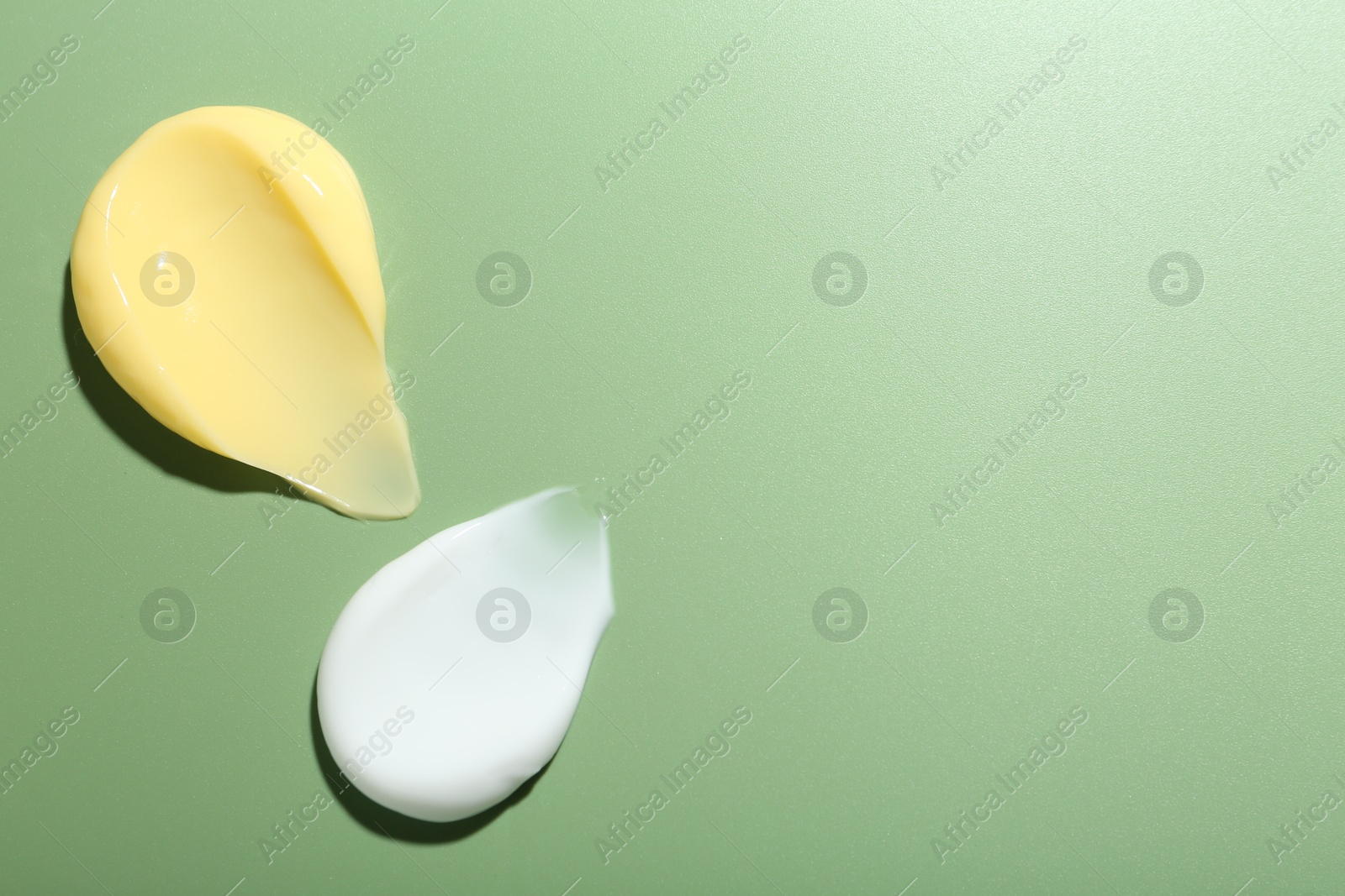 Photo of Cream samples on green background, top view. Space for text