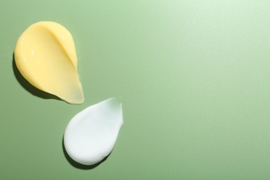 Photo of Cream samples on green background, top view. Space for text