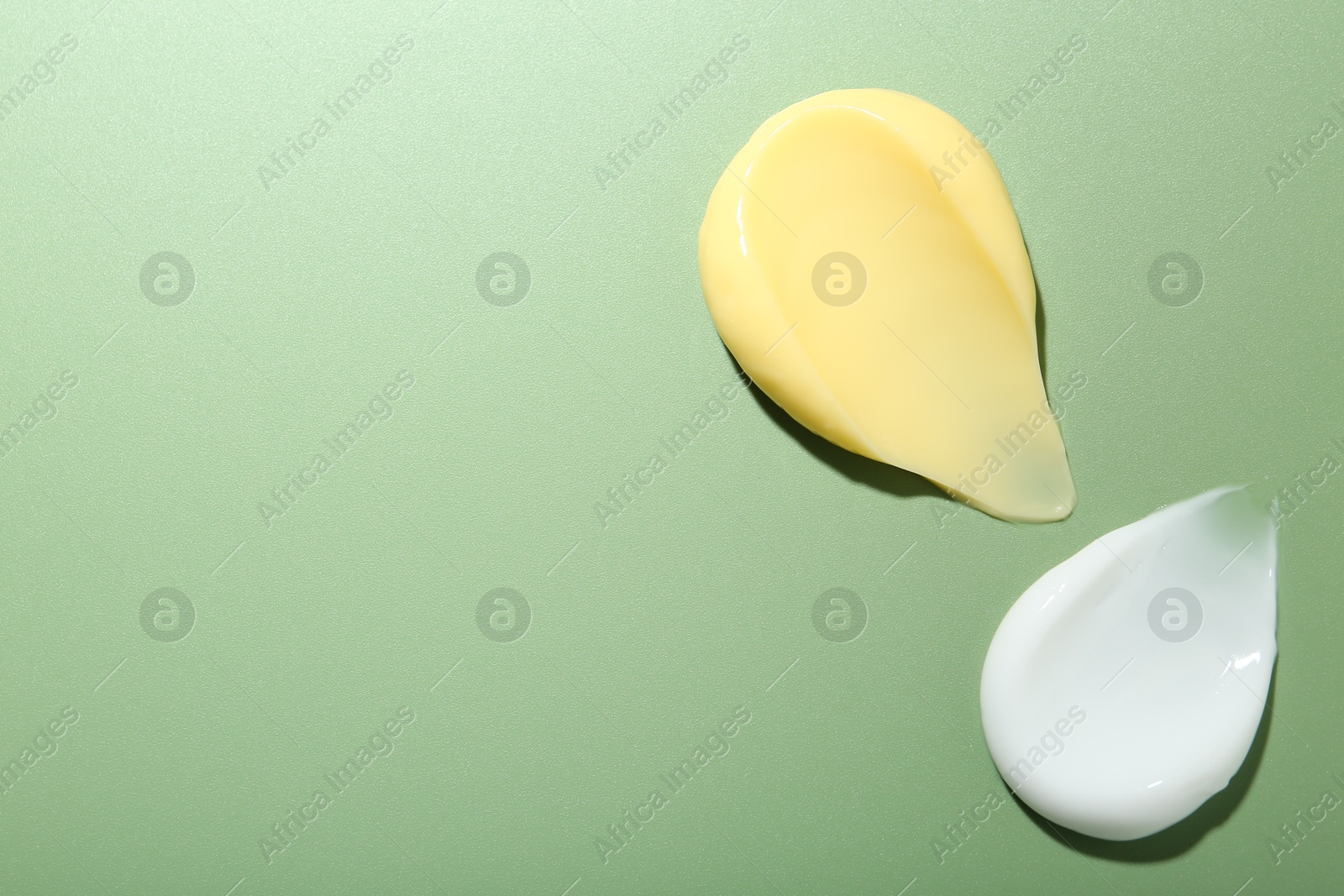 Photo of Cream samples on green background, top view. Space for text