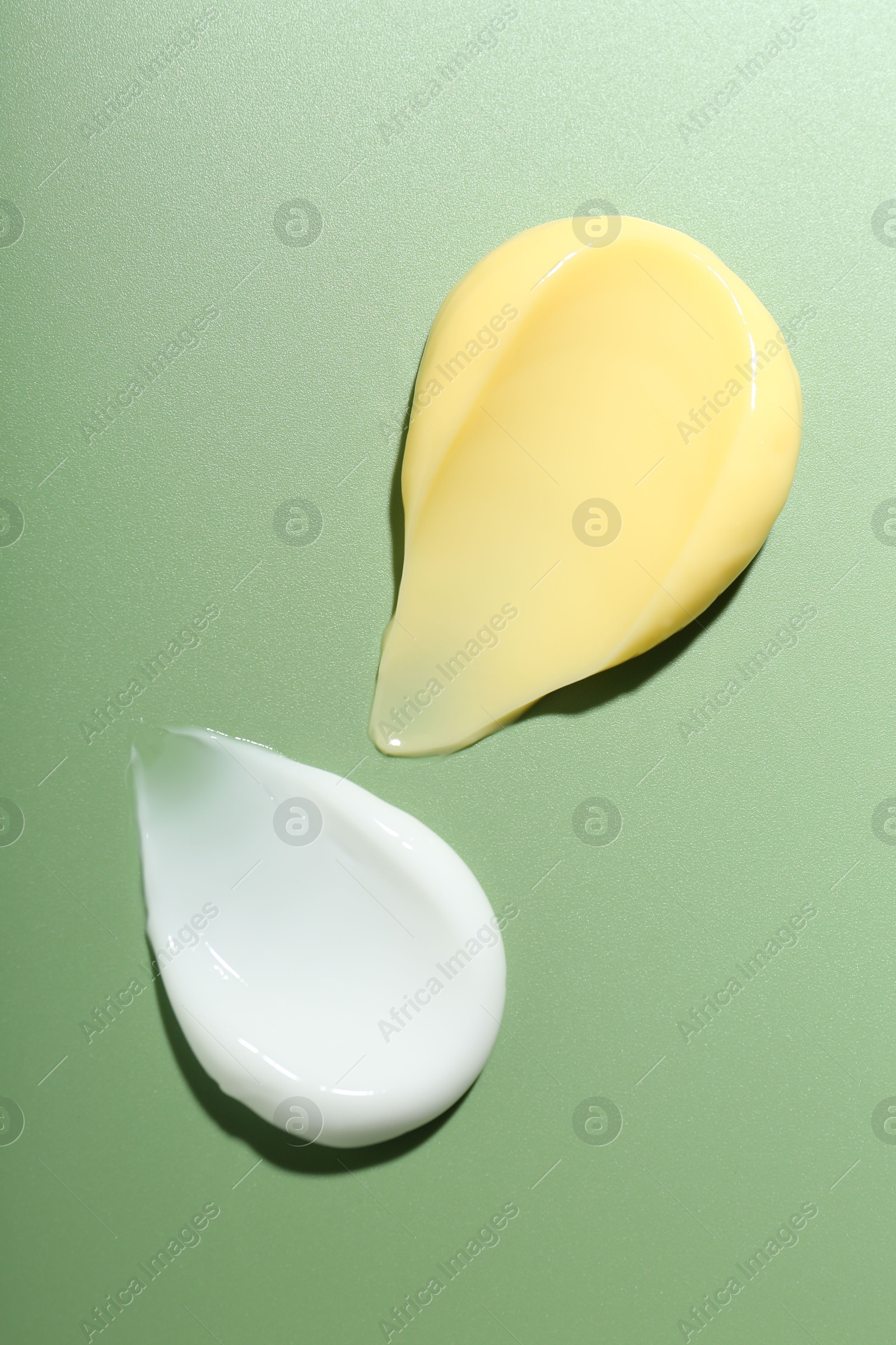 Photo of Cream samples on green background, top view