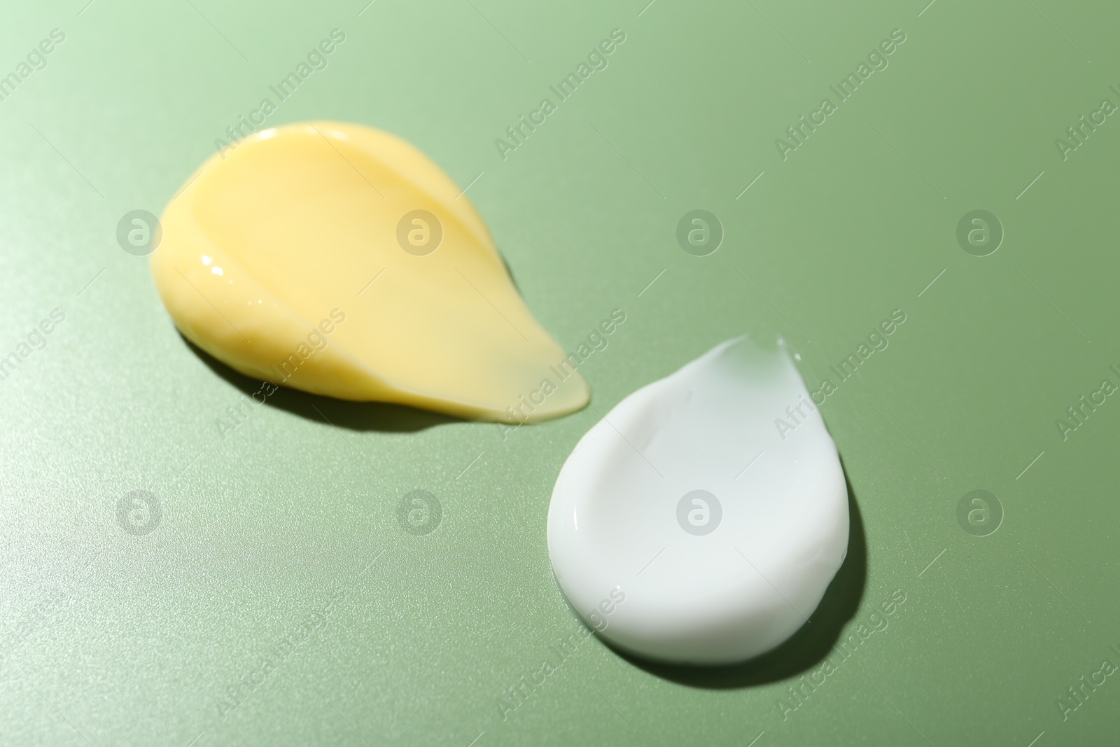 Photo of Cream samples on green background, closeup. Skincare product