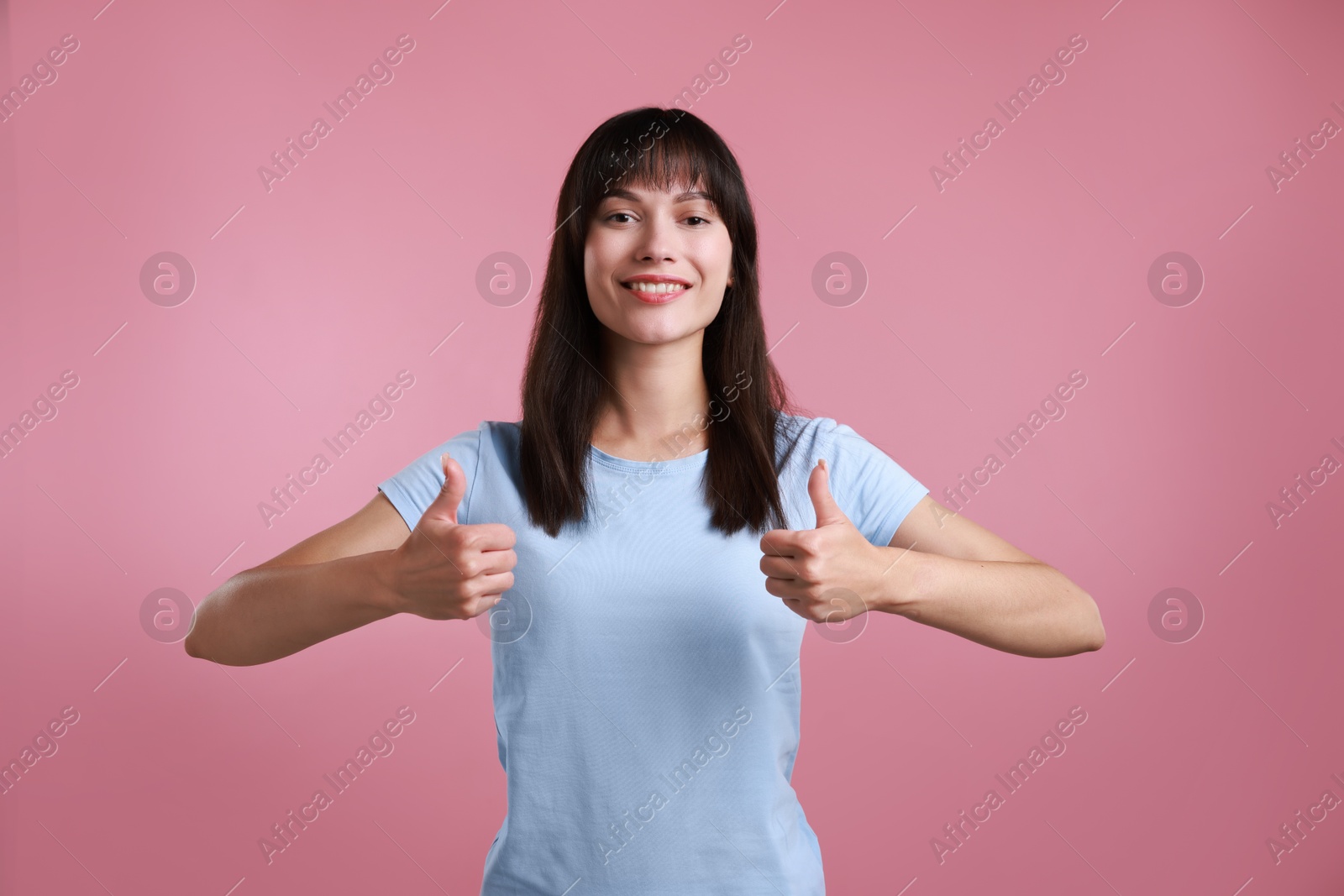 Photo of Happy woman showing thumbs up on pink background. Like gesture