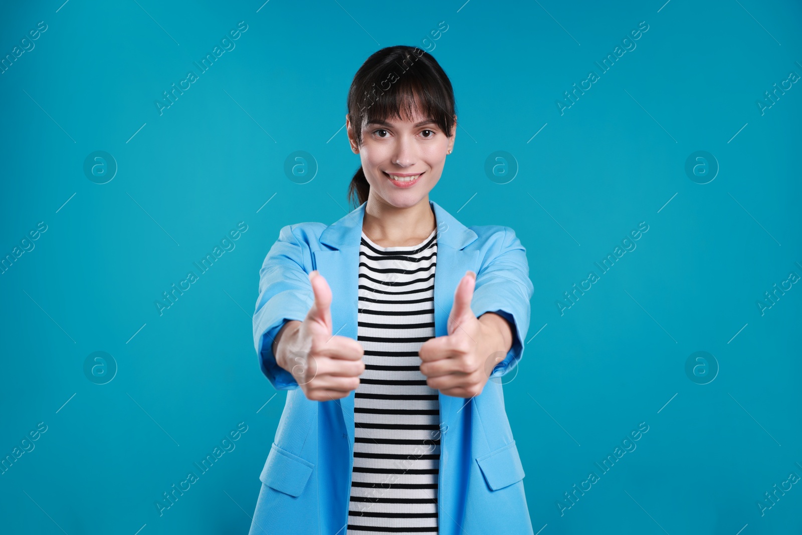 Photo of Happy woman showing thumbs up on light blue background. Like gesture