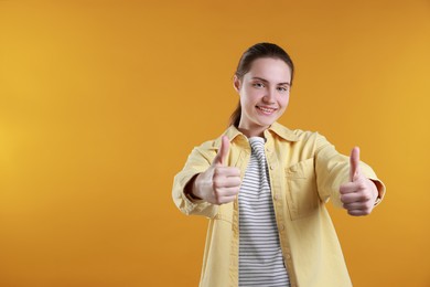 Happy woman showing thumbs up on orange background, space for text. Like gesture