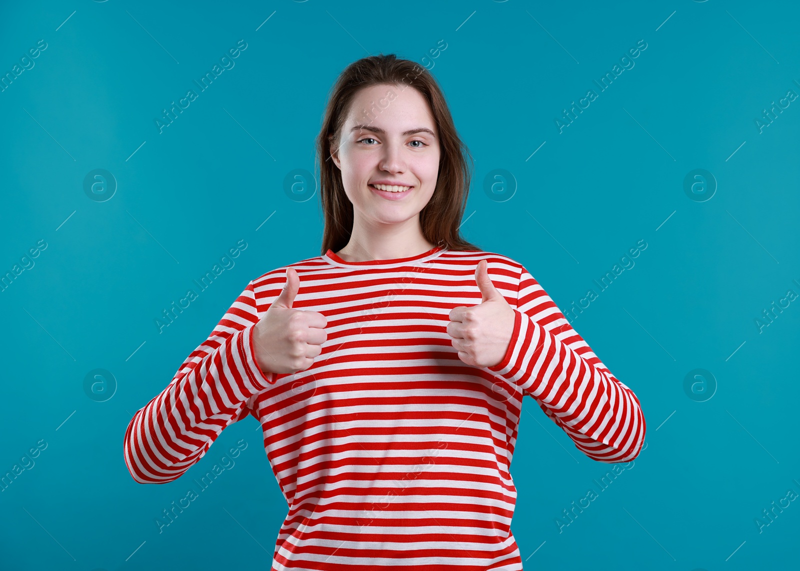 Photo of Happy woman showing thumbs up on light blue background. Like gesture