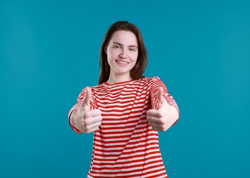 Photo of Happy woman showing thumbs up on light blue background. Like gesture